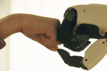Robotarm fra LG CLOiD gir en forsiktig knyttneve mot en menneskehånd, som illustrerer samspill mellom menneske og hjemmerobot.