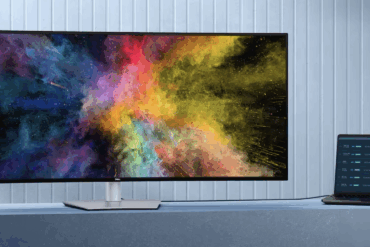 Dell UltraSharp 52-tommers buet 6K-skjerm med bredt ultrawide-panel, vist på skrivebord sammen med kontrollenhet, som demonstrerer høy fargepresisjon og stor arbeidsflate for profesjonell bruk.