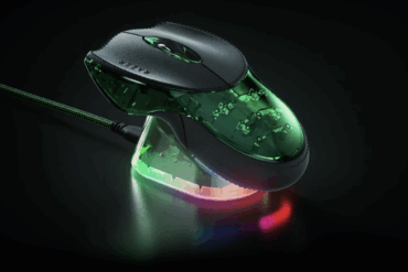 Razer Boomslang 20th Anniversary Edition vist på ladedokk med grønn RGB-belysning og gjennomsiktig underside som viser interne komponenter, plassert på mørk bakgrunn som fremhever den eksklusive designen.