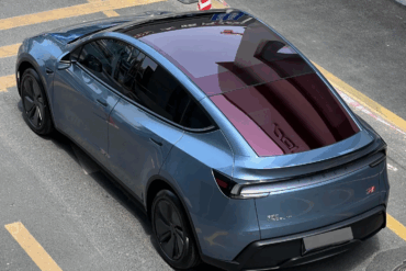 Tesla Model 3 sett bakfra med glasstak og strømlinjeformet design parkert i gate.