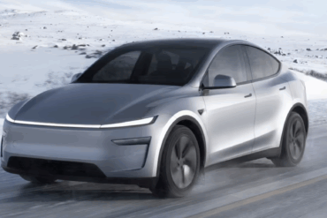 Tesla Model Y kjører på en snødekt vei i vinterlandskap i Norge, med hvite fjell og snø rundt bilen mens den er i bevegelse.