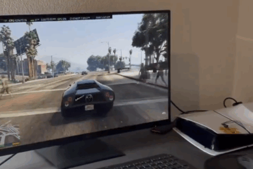 Skjerm som viser GTA V kjørende via Linux på en PlayStation 5, koblet til en ekstern monitor. Konsollen står ved siden av skjermen på et skrivebord.