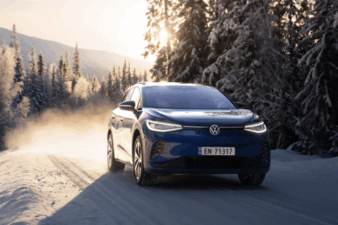 Volkswagen elbil som kjører på en snødekt vintervei omgitt av trær, brukt som illustrasjon i en sak om selskapets økonomiske utfordringer og planlagte kutt i arbeidsplasser.