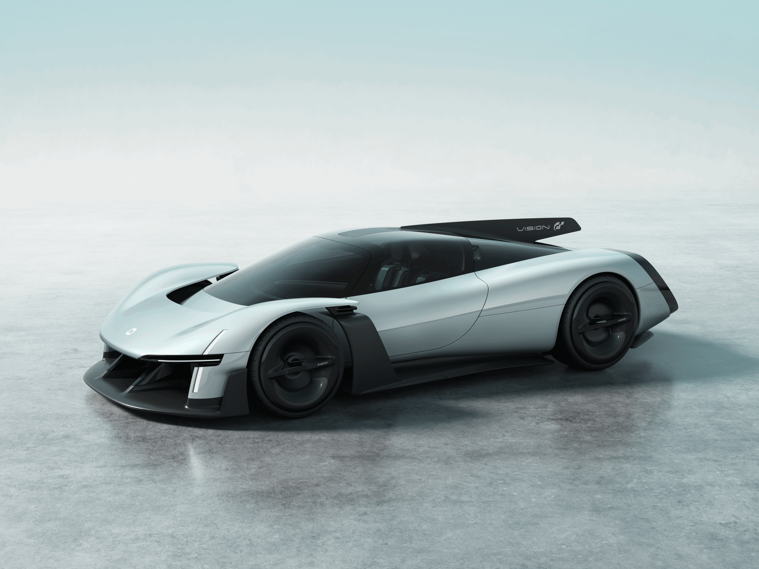 Xiaomi Vision Gran Turismo-konseptet vist i sølvgrå lakk, med ekstremt lav profil, brede hjul, markant frontsplitter og stor bakvinge, plassert på et minimalistisk, lyst studio-gulv.