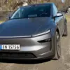 En grå Tesla Model Y står parkert på en landevei i dagslys, fotografert forfra med norske skilter og moderne LED-lysdesign synlig.