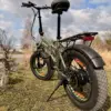 En militærgrønn elektrisk fetsykkel (fatbike) Sharp FS08E parkert på en gressplen med støttebenet nede. Sykkelen er avbildet bakfra i lav vinkel.