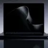 En sort bærbar datamaskin av typen Surface Laptop Ultra vist forfra på en mørk, reflekterende overflate, med en minimalistisk, bølgeformet digital bakgrunn på skjermen.