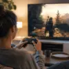 kvinne sitter foran tven og spiller med gamepad