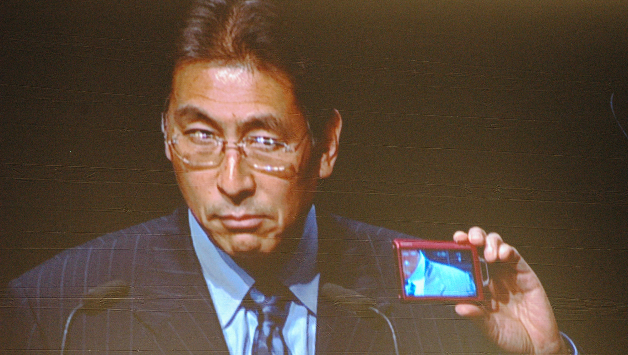 Sonys Europa-sjef Fujio Nishada viser prøver tappert å smile mens han viser fram T200, det ene av Sonys to nye smilekameraer.