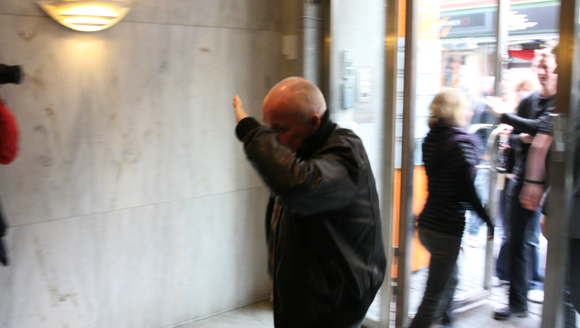 En av de Fast-ansatte skjuler ansiktet i det han går inn i kontorene rett etter at politiet har forlatt bygningen. (Foto: Marius Jørgenrud, Digi.no)