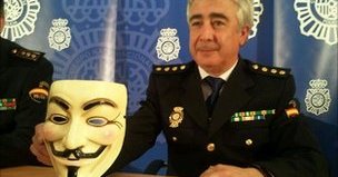 En representant for spansk politi viser stolt fram en Anonymous-maske som skal ha blitt beslaglagt hos en av de tre arresterte.